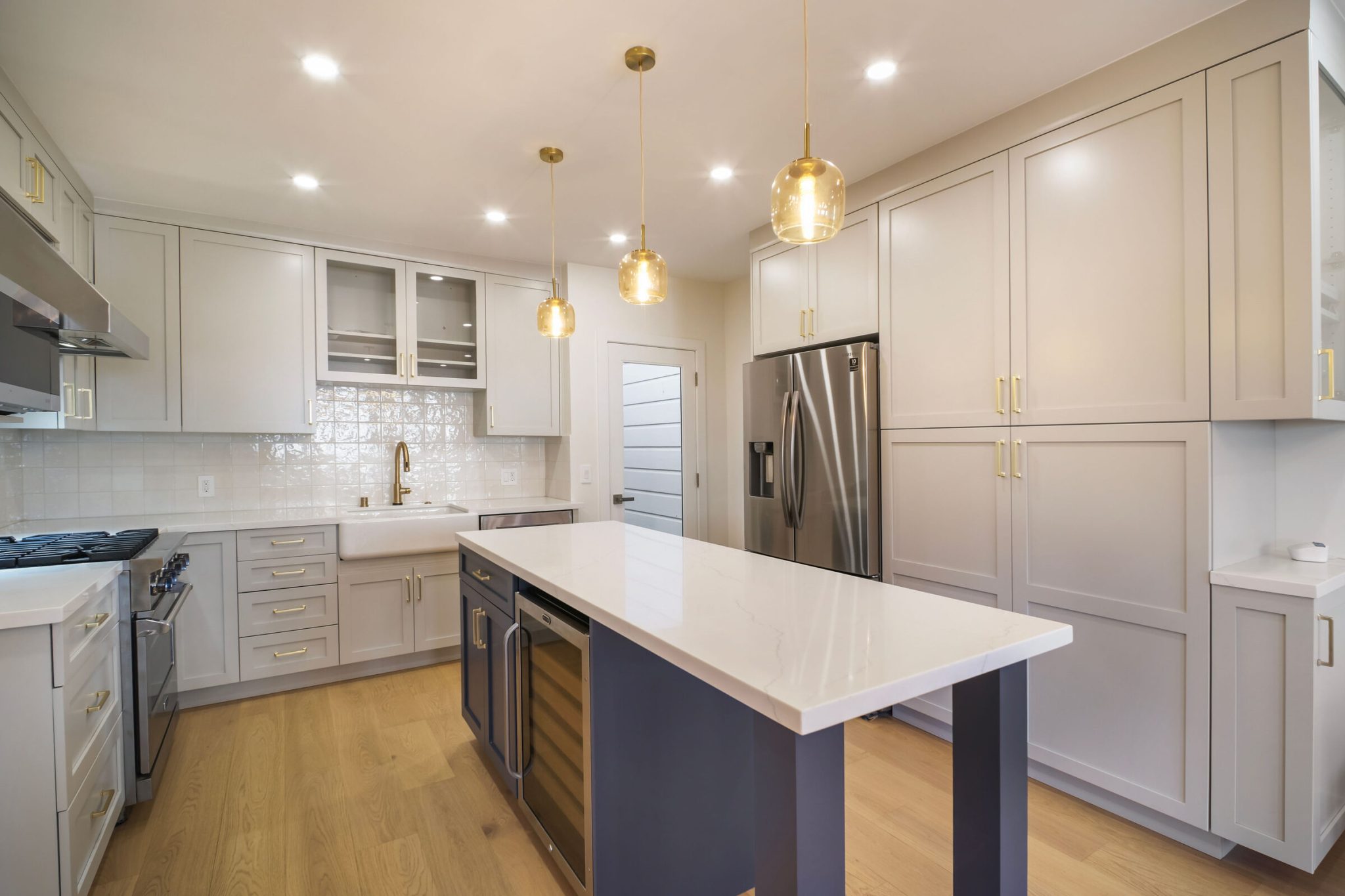 Noe Valley kitchen remodel in San Francisco with shaker cabinets, a navy island with a white quartz top, farmhouse sink and brass hardware