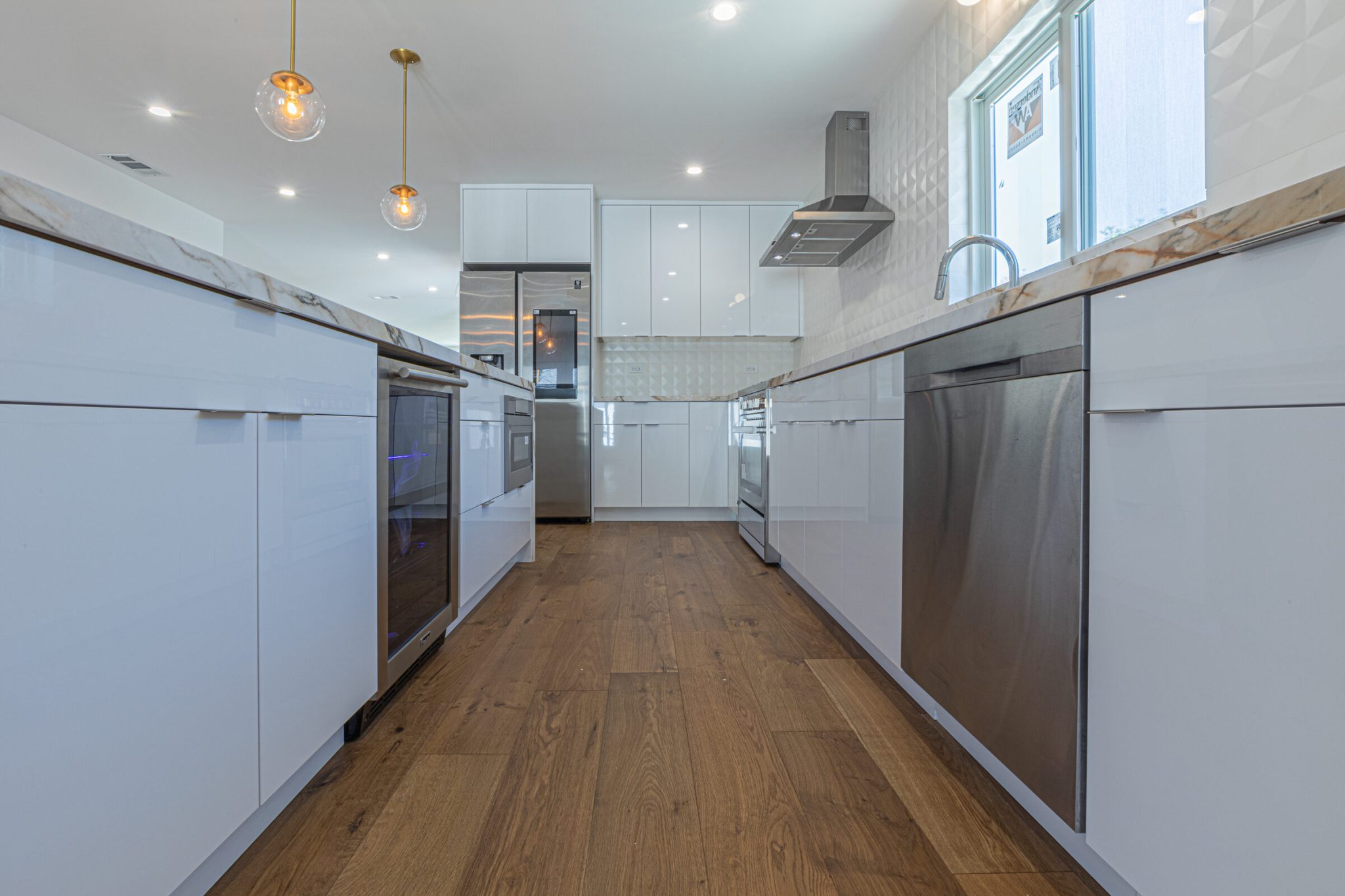 Galley kitchen remodel in San Francisco with full-height white cabinetry, veined stone counters, integrated appliances and wood floors, by WDC